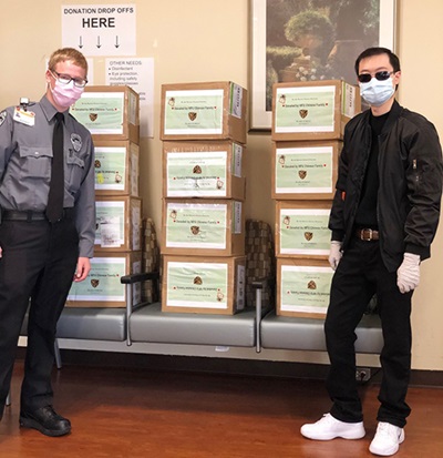 An Asian man in black clothes and a security officer stand beside boxes of N95 masks