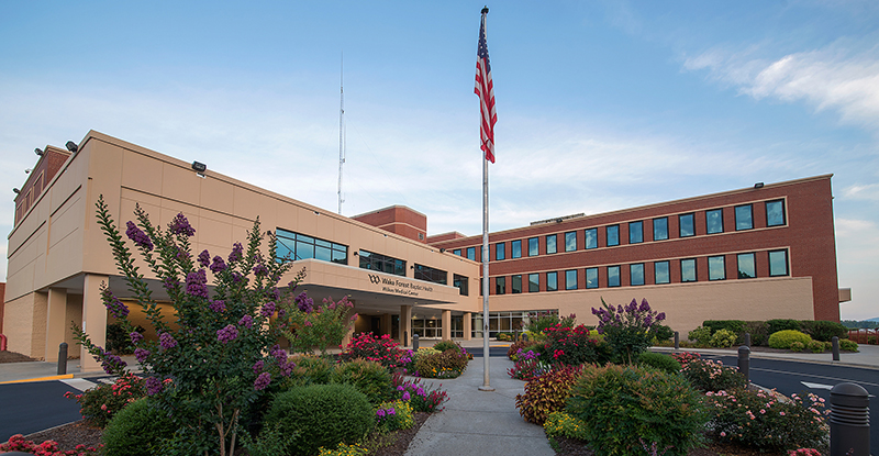 Exterior view of Wilkes Medical Center entrance with flag in foreground and blue sky in background