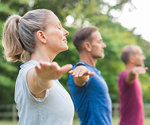 Group of senior people with closed eyes stretching arms at park