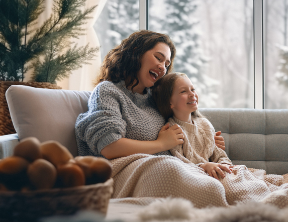 Woman and her daughter on the couch smiling.