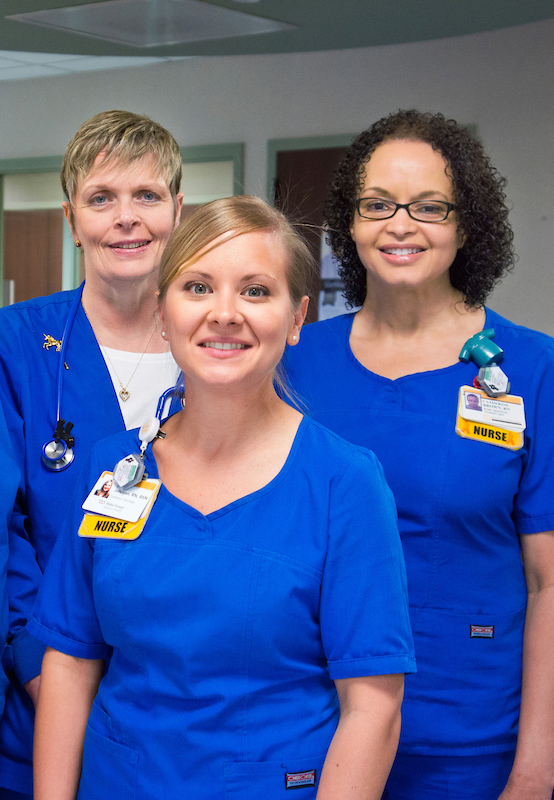 Three female nurses in blue scrubs.
