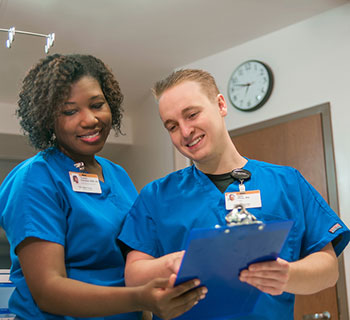 Two nurses checking a clip board. 