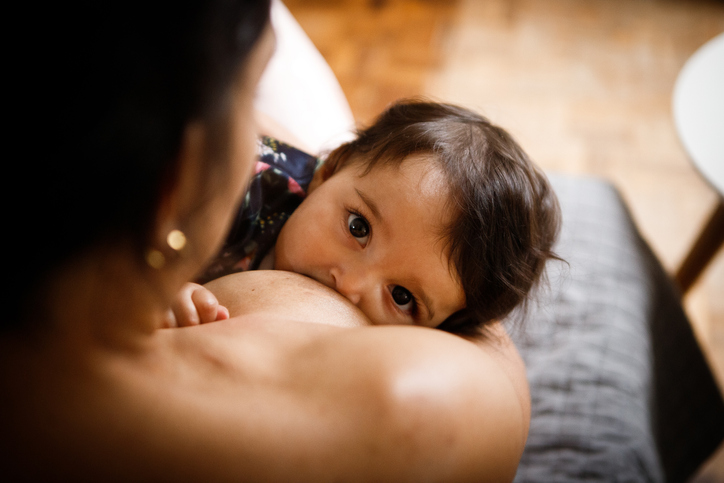 Woman breastfeeding with child looking out.