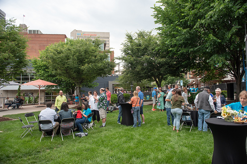 A group of people gathered in a field surrounded by trees.