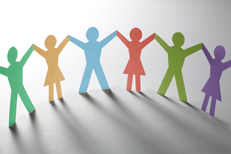 Curving line of paper-cutout people on an orange surface with purple shadows stretching out toward the lower left of the image