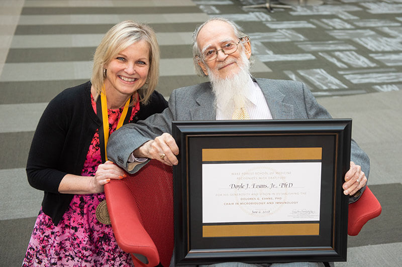 Doyle Evans, PhD, and Dr. Alexander-Miller taking a photo with a framed certificate referencing the Dolores G. Evans Chair.
