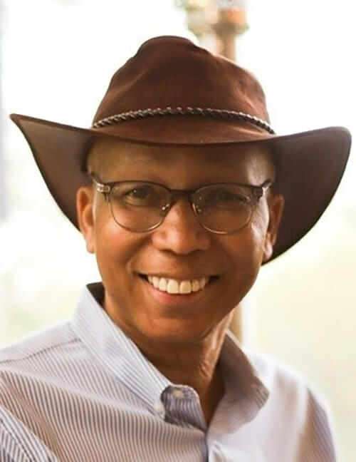 A man wearing a cowboy hat smiling at the camera.
