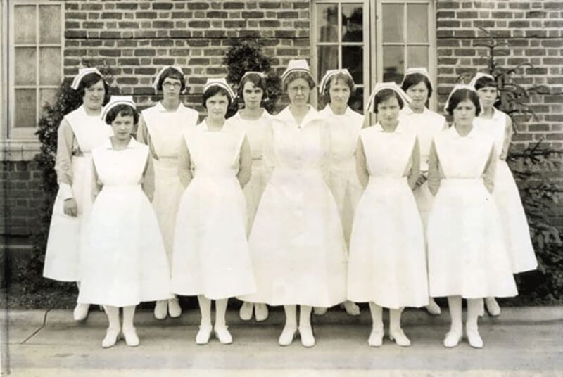 A group of nurses standing in front of a medical building.