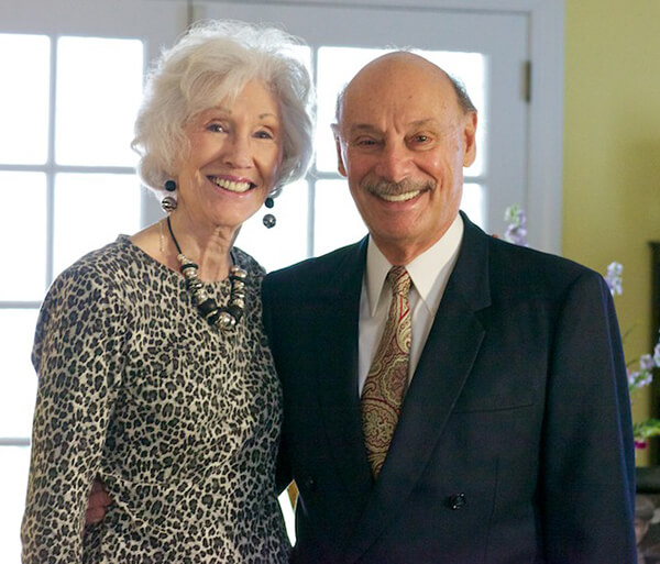 A man and woman standing side-by-side and smiling at the camera.