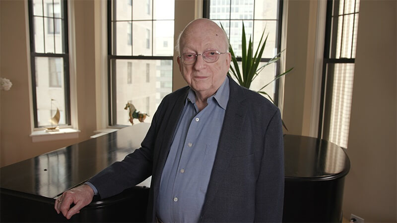 An older man wearing a blazer and looking at the camera.