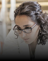 A woman wearing glasses and looking at medical equipment.
