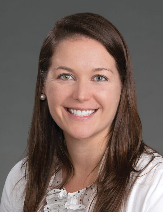 A women with long brunette hair smiling at the camera.