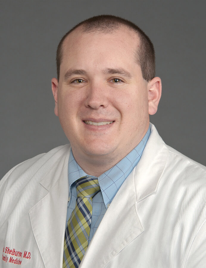 A man wearing a lab coat smiling at the camera.