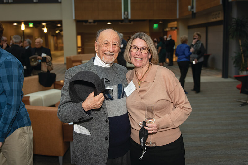 An older man and woman standing side-by-side smiling at the camera.