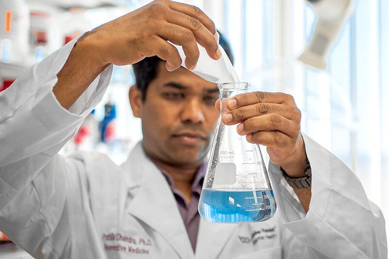 A medical professional pouring liquid into a beaker.