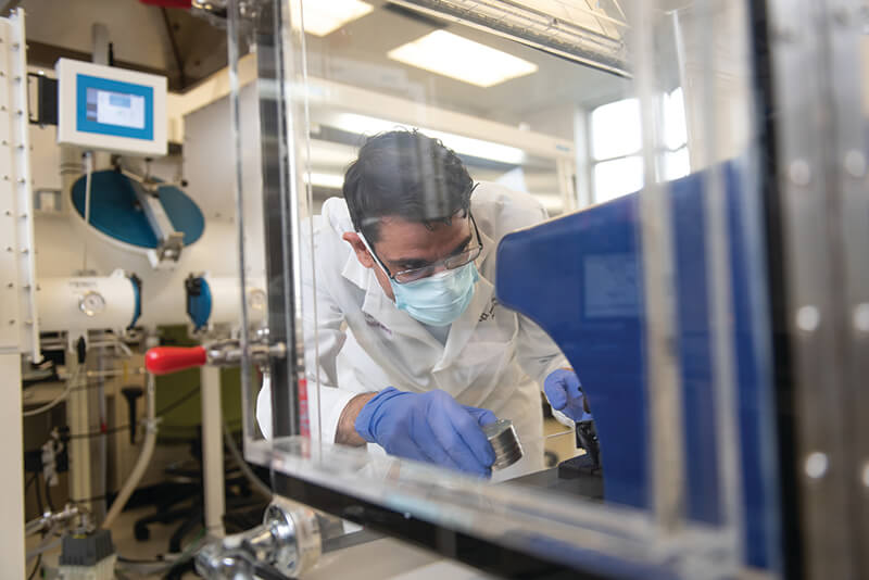 A medical professional wearing a mask and working with medical equipment.