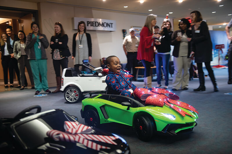 A young girl playing in a green toy car.