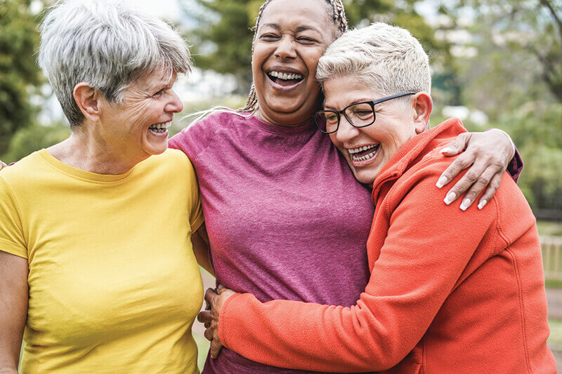 Three older women in a group hug.