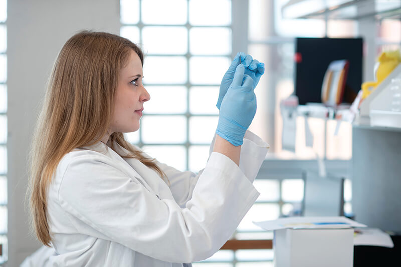 A woman wearing medical clothing looking at a slide.