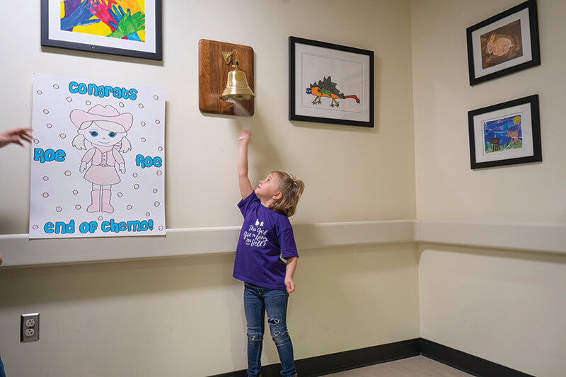 A young girl ringing a bell.