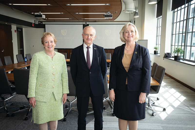 Two women and one man standing side-by-side smiling at the camera.