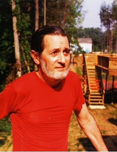 A man wearing a red shirt and looking off into the distance.