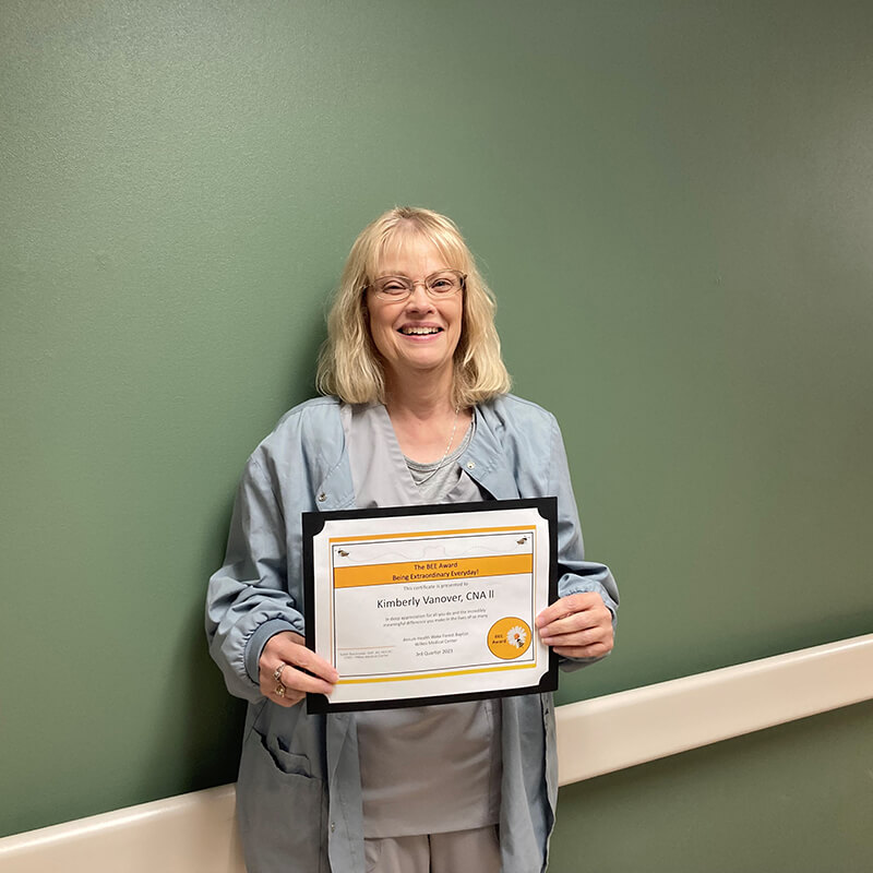 A woman holding a certificate and smiling at the camera.