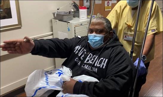 Booker signals that he is heading home as he is wheeled out of Wake Forest Baptist Medical Center. 