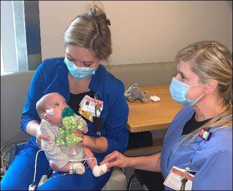 River looks up at one of his nurses, Hannah Privette, as he prepares to go home.