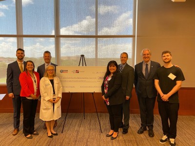 Group photo of eight people in front of giant check.
