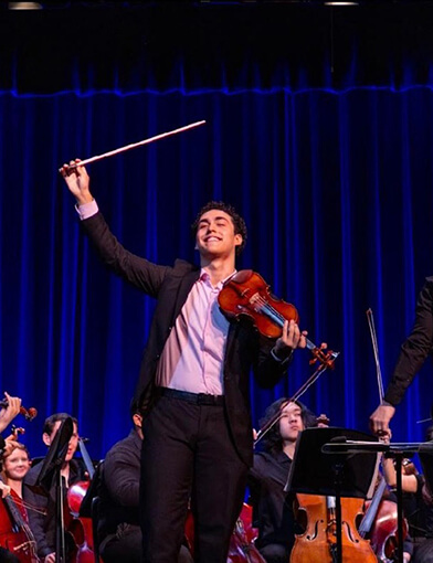 Garikoitz Gainza playing violin on stage while in a black suit.