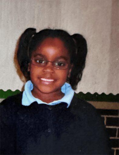 A young Nneayo Okabuonye smiling while wearing a black shirt.