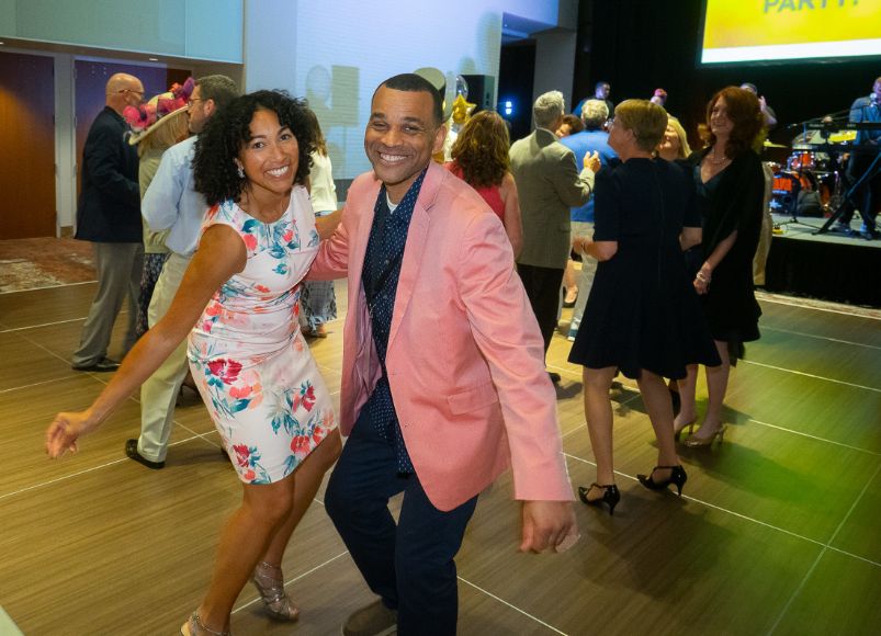 Photo of woman in white dress dancing with man in salmon jacket and black pants at Alumni Weekend 2023 at Wake Forest University School of Medicine.