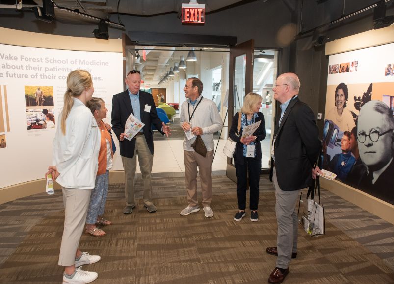 People standing around admiring the deacon gallery at Alumni Weekend 2023 at Wake Forest University School of Medicine.