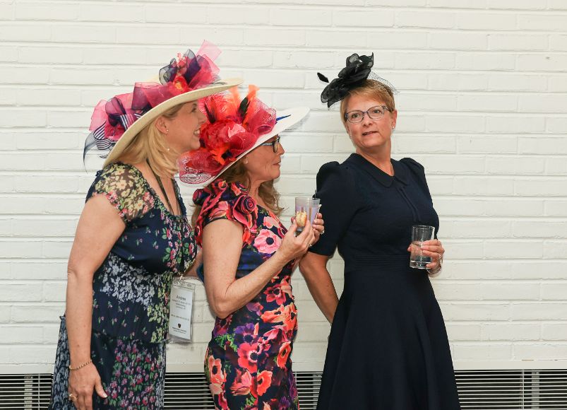 Women in black and pink dresses wearing impressive and beautiful Kentucky Derby hats at Alumni Weekend 2023 at Wake Forest University School of Medicine.