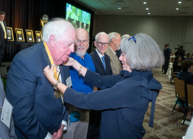 Man receiving a medal from a woman at Alumni Weekend 2023 at Wake Forest University School of Medicine.
