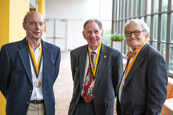 Three men stand in sunlit hallway after being inducted into the Bowman Gray Society in 2019