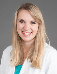 White woman with long blonde hair and wearing a white coat