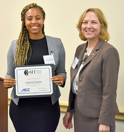 Lauren West-Livingston accepts certificate from Bonnie Ferri while standing next to a podium and US flag