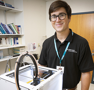 Jeffrey Powell, MD Class of 2022, smiles as he stands in a lab behind some equipment