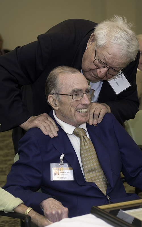 Timothy Pennell leans over to hug Richard Janeway at a ceremony honoring Janeway