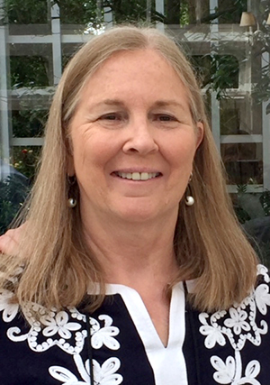 Woman with shoulder-length blonde hair and wearing a black and white top smiles