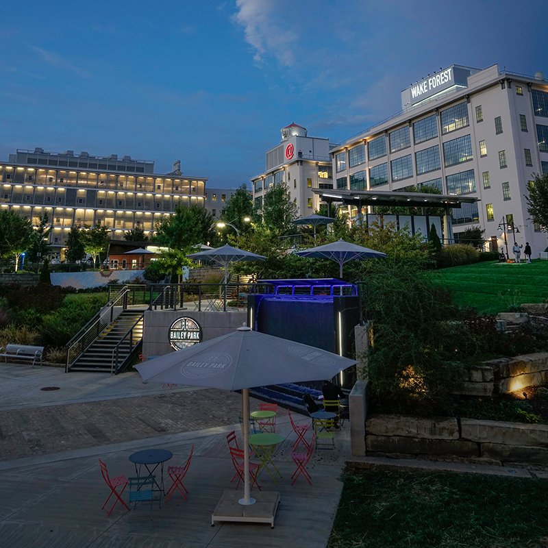 Evening view looking up at two buildings with a greenway park in the foreground