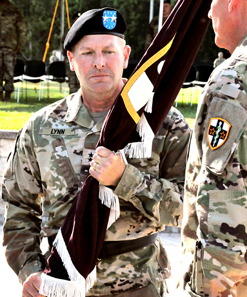 A man wearing a military uniform holding a flag.