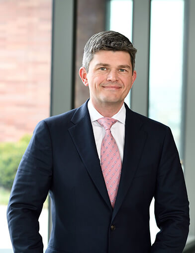 A young man wearing a suit and tie smiling at the camera.