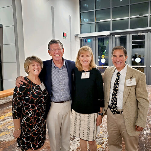 Four people standing side by side smiling at the camera.