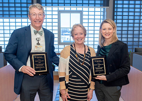 Two people holding plaques and standing next to an older woman.