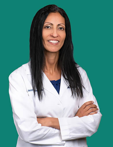 A young women wearing a white coat smiling at the camera.