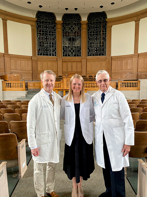 Three people wearing white coats smiling at the camera.