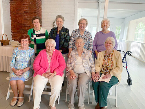 A group of older women sitting and smiling at the camera.